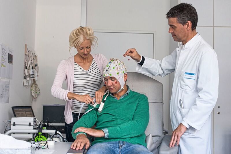 Laura Tiemann, Erstautorin der neuen Studie zur Schmerzwahrnehmung, bereitet zusammen mit Markus Ploner, Heisenberg-Professor für Human Pain Research an der TUM, eine Person für die EEG-Messung vor. (TU München/ Kurt Bauer)