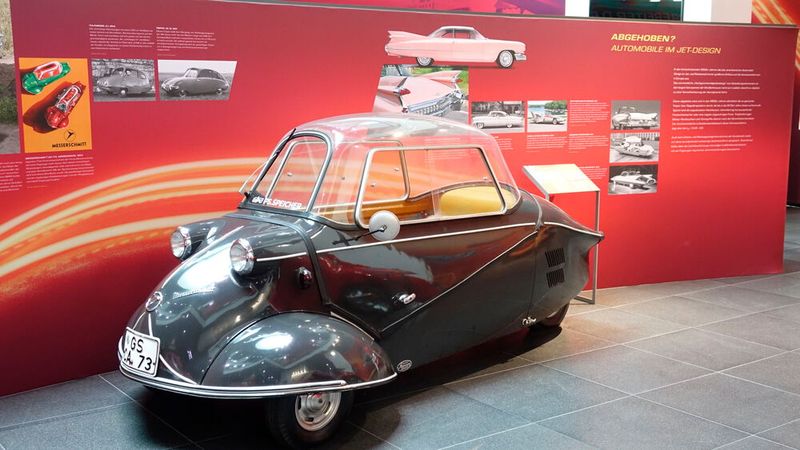Der Messerschmitt-Kabinenroller war ein Rollermobil des deutschen Konstrukteurs Fritz Fend. Da diesem das Kapital fehlte, seine Produktion zu vergrößern, wandte er sich an Willy Messerschmitt. Der neu konstruierte Kleinstwagen hatte drei Räder und zwei hintereinander angeordnete Sitze, sodass ein ungewöhnlich schmaler, aerodynamisch günstiger Fahrzeugkörper gestaltet werden konnte. Die beiden Vorderräder waren lenkbar. Der Motor war im Heck des Fahrzeugs eingebaut und trieb das Hinterrad an. (Bild: Dominsky – VCG)