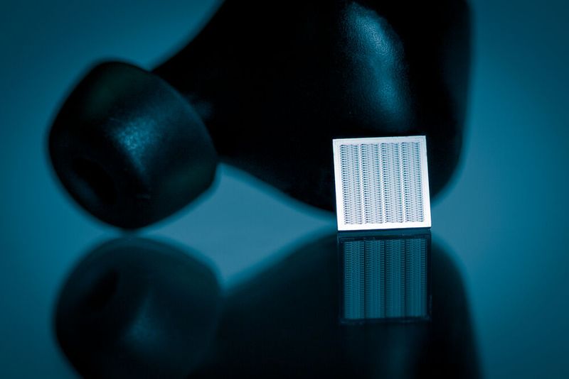 Lautsprecher aus 100 Prozent Silizium sind klein, leicht, energieeffizient und gut skalierbar. Der hier abgebildete MEMS-Chip kann in den dahinter liegenden Earbud eingesetzt werden. (Bild: Arioso Systems)