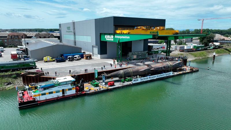 Zunächst wurde U17 in der Kieler Werft der Thyssenkrupp Marine Systems demilitarisiert. Nach einer gründlichen Reinigung inklusive der Entfernung von Muscheln, Algen und Co. war das U-Boot transportfertig, konnte verladen und ins Technik Museum Speyer transportiert werden. Nach dessen Ankunft machten sich die Mitarbeiter der Technik Museen Sinsheim Speyer daran, U17 für den Weitertransport nach Sinsheim vorzubereiten. Zum Beispiel wurde das U-Boot von den tonnenschweren Batterien und Tauchgewichten befreit, zu deren Ausbau in Kiel die Zeit fehlte. Dadurch war es nicht nur leichter für den Weitertransport, sondern auch für die anstehenden Drehungen des U-Boots, um unter diversen Brücken hindurch und über Bahnübergänge gefahren werden zu können. Nach dem Positionieren der speziell angefertigten Drehvorrichtung erfolgte im November 2023 die erste erfolgreiche Probedrehung um 73 Grad. (Bild: Auto - Technik - Museum e.V.)