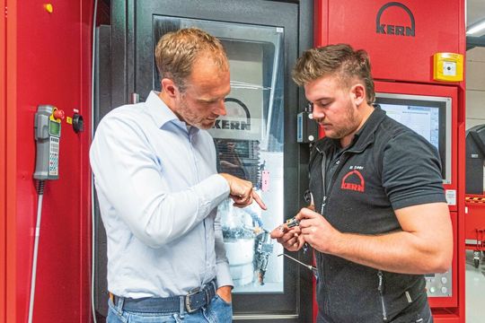 Kern Microtechnik fertigt die primär aus Edelstahl, Messing oder Arcap bestehenden Insertgehäuse der Glasfaserstecker kompromisslos präzise. Hier erklärt Alexander Stauder, Werkleiter der Kern-Auftragsfertigung, seinem Mitarbeiter, worauf es dabei ankommt.(Bild:  Kern Microtechnik)