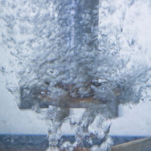 Detailaufnahme aus dem Reaktor: Unten ein Gasverteiler mit Luftblasen, oben ein Rührer