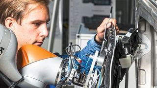 Sinnvolle Arbeitsteilung: Der Roboter trägt die Last und reicht an, der Werker unterstützt ihn beim passgenauen Einsetzen eines Bauteils. (Arena2036/ Rainer Bez)