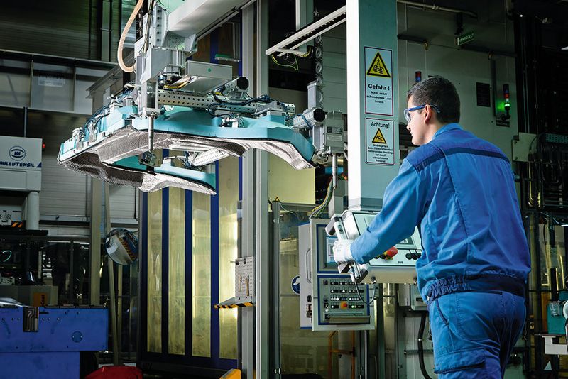 BMW-Group-Werk Landshut: Im Innovations- und Produktionszentrum CFK bringt ein Mitarbeiter einen BMW-i8-Seitenrahmen in die RTM-Presse ein. (BMW Group)