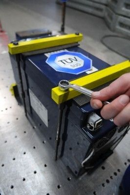 Eine Batterie wird für einen Crashtest auf dem Versuchsschlitten des Crashtestzentrums des TÜV SÜD fixiert. (Bild: TÜV SÜD)