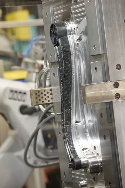 Das neue Langfaser-Direktspritzgießen präsentierte Arburg auf der K 2013 mit dem Umspritzen eines endlosfaserverstärkten Thermoplast-Einlegers (Tepex-Organoblech). In 40 s wurde ein über 500 mm langer und nur 200 g schwerer hochfester Compositehebel gefertigt. (Bild: Arburg)