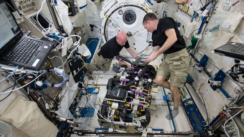 Astronauts working on the CDRA. (Source:  NASA)