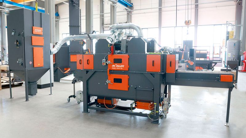 The installation of the flexible wire mesh belt blast machine RSAB 370 T1+1 (center) with Atex compliant dust collector (left) helped reduce the personnel costs for de-flashing of housing components by nearly 50 percent. (Source: Rösler Oberflächentechnik)
