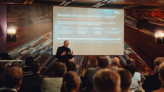 Vortrag von Heinz-Peter Beckemeyer, Director of Cybersecurity & Functional Safety Marketing bei Texas Instruments, über die Auswirkungen des Cyber Resilience Acts (CRA) auf die Embedded-Entwicklung. Auf dem ersten Munich Embedded Kongress tauschten sich 80 lokale Entwickler der Münchner Embedded-Community über Trendthemen und Ideen aus. (Bild: NICO FLOROW)