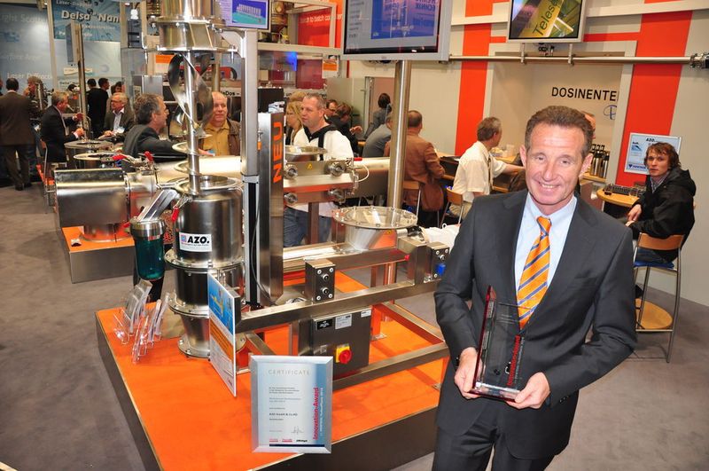 Reiner Zimmermann, Geschäftsführender Gesellschafter bei AZO, zeigt stolz den Innovation-Award in der KategorieGrundverfahren für Pulver und Schüttgüter. Im Hintergrund das prämierte Produkt: die Wirbelstrom-Siebmaschine DA mit vertikaler Ausrichtung. (M.Henig/PROCESS) (Archiv: Vogel Business Media)