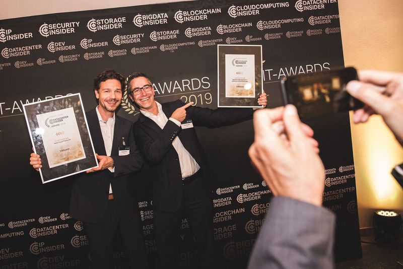 Auf dem Weg in die Bar verleitet die Fotowand noch einmal zum Gewinnerbild: Jürgen Schaub und Horst Robertz nehmen jeweils einen Award für VMware mit. (Bild: artful rooms / VIT)