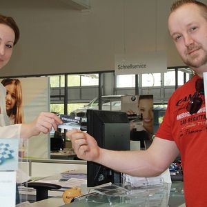 Aleksandra Ristic, die das Marketing im BMW-Autohaus Overdreef verantwortet, übergibt einem Kunden die Treuekarte.